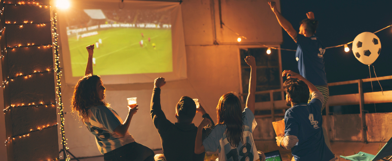 people watching football on projector screen outside